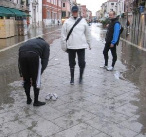 I am fascinated by the problem-solving approach taken by the man on the left.  His knee-high socks were drenched (see wet footprints) and he is rolling up his trousers.  I'm hoping he had the sense at least to have taken off his shoes before he stepped into the water.  But why didn't he take off his socks as well?